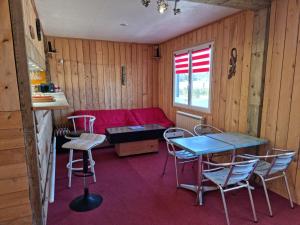 sala de estar con sofá rojo, mesas y sillas en Camping Village Nature D'O, en Hillion