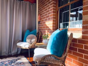 a patio with chairs and a table with blue pillows at The Shopkeepers Quarters in Tenterfield