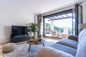 a living room with a blue couch and a table at LOS ARQUEROS GOLF APARTMENTS in Benahavís