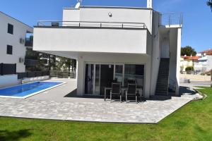 ein weißes Haus mit einer Terrasse und einem Pool in der Unterkunft Villa Dalija in Biograd na Moru