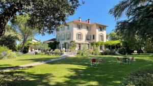 una grande casa con sedie in cortile di Maison d'hôtes Le Parc a Labruguière