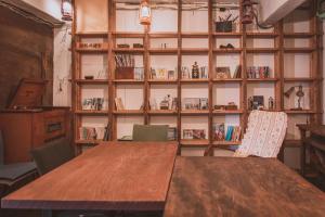 a table and chairs in a room with a book shelf at ゲストハウスまたたび in Matsumoto