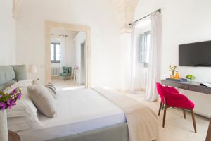 a white bedroom with a large bed and a red chair at Masseria San Giovanni - Epoca Collection in Fasano