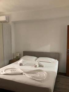 uma cama branca com lençóis brancos e almofadas em Villa 151 em Saranda
