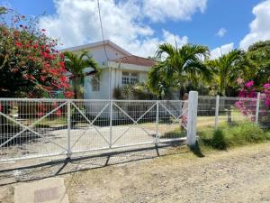 a fence in front of a house with flowers at Villa spacieuse avec piscine privée - Le Vauclin in Le Vauclin