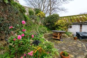 a garden with a table and some flowers at Waterwitch Cottage in Newquay