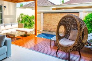 a patio with a wicker chair and a couch at The residence resort Villa 1bdr Private Pool in Phuket Town