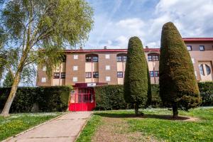 um edifício com uma porta vermelha e alguns arbustos em RESIDENCIA HOSPITAL DEL REY em Burgos