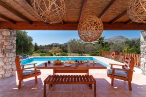 eine Terrasse mit einem Tisch und Stühlen sowie einem Pool in der Unterkunft Olive Private Villa Swimming Pool 5 BDR Rhodes Kolymbia in Kolymbia