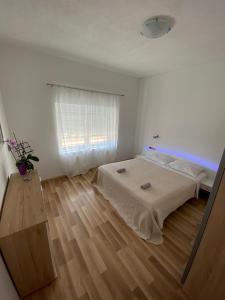 a white bedroom with a bed and a wooden floor at Rojena vala - Neretva in Komin