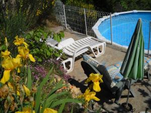 un banco y una sombrilla junto a la piscina en Gîte Trinacria, en Breil-sur-Roya