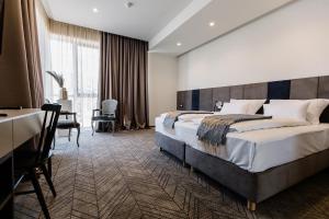 ein Hotelzimmer mit einem großen Bett und einem Schreibtisch in der Unterkunft Hotel Buna Mostar in Buna