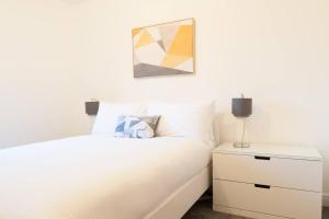 a bedroom with a white bed and a nightstand at *NEW* Central Derby Apt, with Parking - Sleeps 6 in Derby