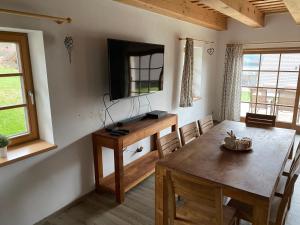 a dining room with a table and a television on the wall at Chalupa Pecivál Lipno in Lipno nad Vltavou