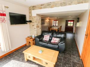 a living room with a black leather couch and a table at The Stable Barn in Llandysul