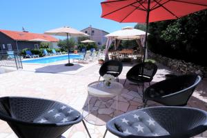 un patio con sillas y una mesa con sombrilla en Villa Mendula Trogir - Luxury beachfront villa with large pool area surrounded by organic vegetable garden and olive trees en Trogir