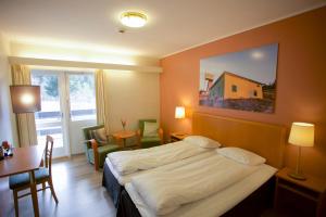Cette chambre comprend un lit, un bureau et une table. dans l'établissement Utsikten Hotell Kvinesdal, à Kvinesdal