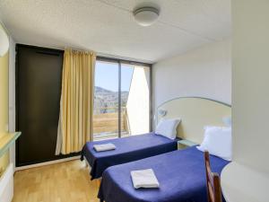 MiremontにあるVacancéole - Le Domaine de Confolantのベッド2台と大きな窓が備わる客室です。
