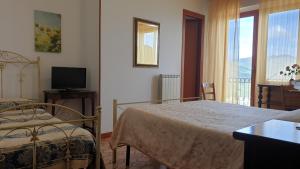 a bedroom with two beds and a television and a window at B&B Casa Michele in Taormina
