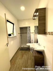 a bathroom with a sink and a toilet and a shower at Ferienwohnungen AKH Home in Sankt Wendel +9 photos