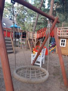 un parque infantil con un columpio y un tobogán en domki apartamenty Nasza Chata - 4 minuty od plaży, en Pobierowo