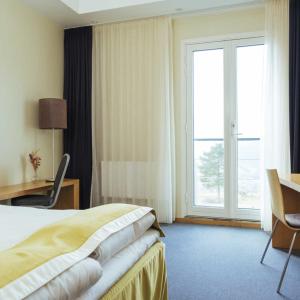 Habitación de hotel con cama, escritorio y ventana en Utsikten Hotell Kvinesdal, en Kvinesdal