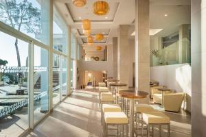 un restaurante con mesas, sillas y ventanas grandes en MarSenses Ferrera Blanca Hotel Family en Cala d´Or