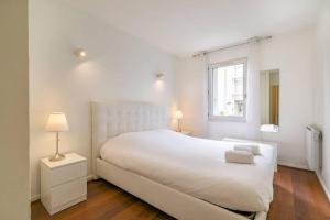 a white bedroom with a white bed and a window at Le Marpaux in Dijon