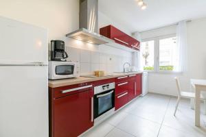 a kitchen with red cabinets and a microwave at Le Marpaux in Dijon