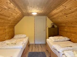 2 Betten in einem Zimmer mit Holzwänden in der Unterkunft Harcsáztat-Lak in Tiszaderzs