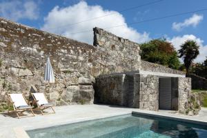 a villa with a swimming pool in front of a stone wall at Casa dos Cabeçudos in Afife