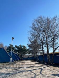 a parking lot with trees and blue dumpnets at Energetikas • nameliai prie jūros in Šventoji
