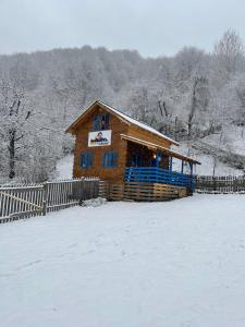 une cabane en rondins dans la neige avec une clôture dans l'établissement Casa Brună, à Băile Olăneşti