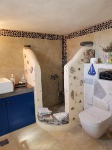 y baño con ducha con paredes de piedra y aseo. en Apo Petra en Agia Marina Aegina