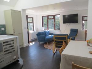 sala de estar con TV y sofá azul en Willow Cottage, en Dersingham