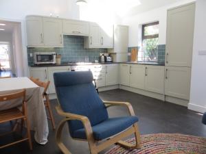 a kitchen with a blue chair and a table at Willow Cottage in Dersingham