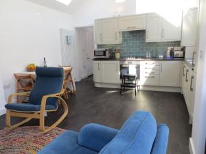 una cocina con armarios blancos y sillas azules. en Willow Cottage, en Dersingham