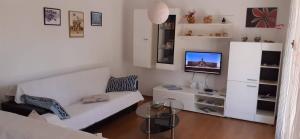 a living room with a white couch and a tv at Bright and spacious apartment with outdoor space in Kaštela