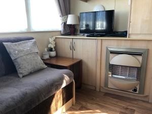 BactonにあるNorfolk Lavender Caravan - Sleeps 4 - WiFi and Sky TV Includedのリビングルーム(テレビ、テレビ、ソファ付)