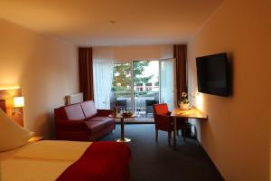 a hotel room with a bed and a chair and a television at Hotel Häfner in Bad Schonborn
