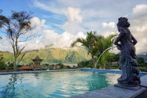 a statue next to a swimming pool with a fountain at Mapa Lake View Bungalow in Kintamani
