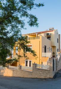 a yellow building on a stone wall next to a street at Family-villa Nikolaos with Playground, private pool & BBQ in Roussospítion