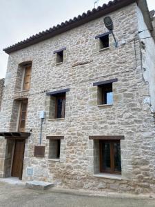 a large stone building with windows and a door at Precioso loft rural con estufa de leña panorámica in Torre del Compte