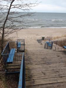 un paseo marítimo que conduce a una playa con bancos azules en domki apartamenty Nasza Chata - 4 minuty od plaży, en Pobierowo