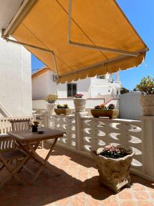 um pátio com uma mesa de madeira e um guarda-chuva em Le case di Nunzia em Lampedusa