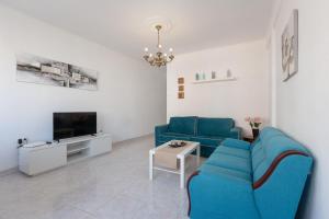 salon z niebieską kanapą i telewizorem w obiekcie Centric apartment in Malaga w Maladze