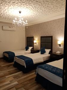 Habitación de hotel con 2 camas y lámpara de araña. en مساس الخليج Mesas Gulf وحدات سكنية en Dammam