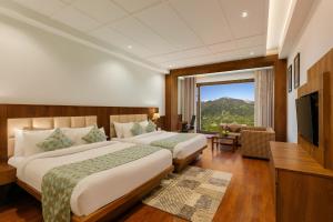 a hotel room with two beds and a large window at The Orchid Manali - a Boutique Hotel in Manāli