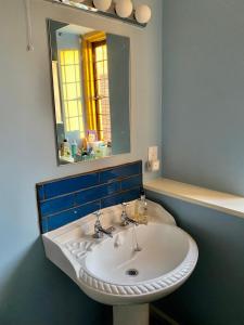 La salle de bains est pourvue d'un lavabo blanc et d'un miroir. dans l'établissement The Grange, à North Cadbury