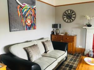 a living room with a couch and a clock on the wall at The Gables in Crail